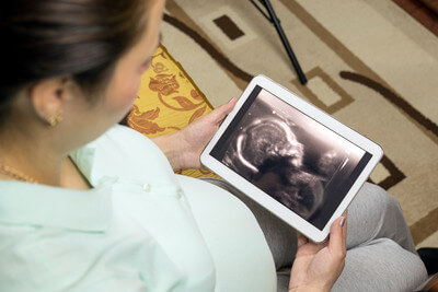 Pregnant woman watching ultrasound picture of their child on the tablet